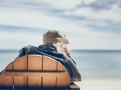 elderly man on the beach sitting in a wooden chair