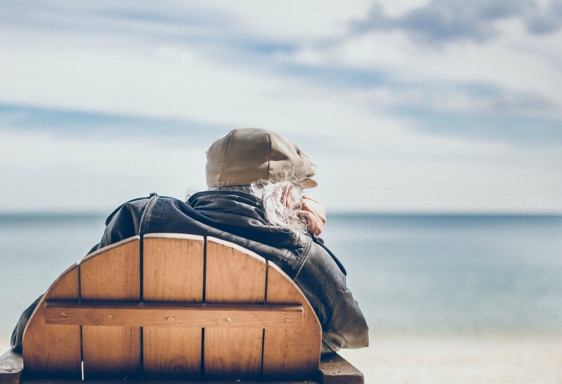 elderly man on the beach sitting in a wooden chair