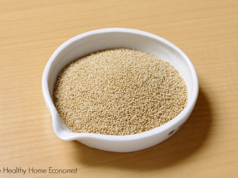 small white bowl of pearl millet on a cutting board