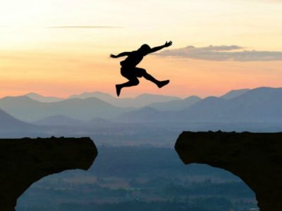 man leaping a gap in a cliff