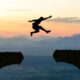 man leaping a gap in a cliff