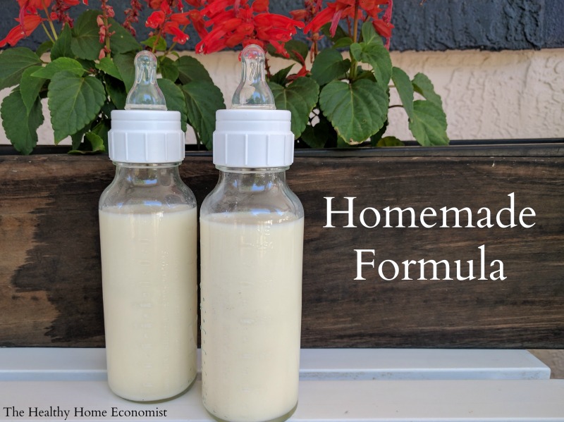 two glass bottles of homemade baby formula on a white table