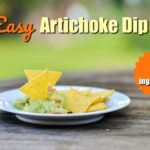homemade artichoke dip on a white plate with tortilla chips