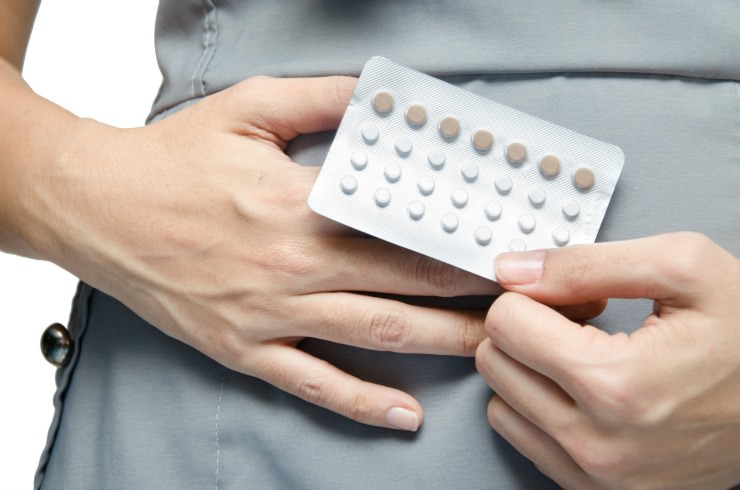 woman holding blister pack of oral contraceptive pills