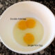 double yolk egg compared to single yolk egg in white bowl