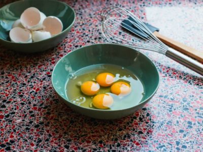 four perfectly cracked eggs in a bowl with a whisk