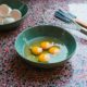 four perfectly cracked eggs in a bowl with a whisk