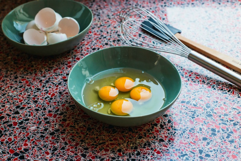 four perfectly cracked eggs in a bowl with a whisk