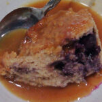 bread and butter pudding in white bowl with spoon