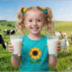 little girl holding a glass of cow milk and a glass of goat milk