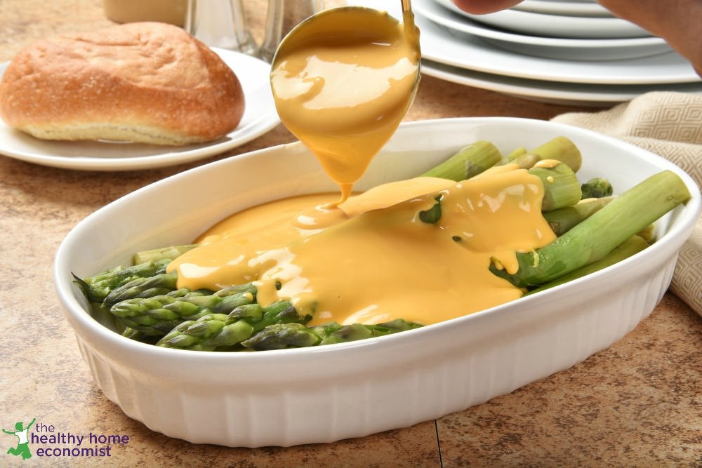 welsh rarebit poured over asparagus in a white bowl
