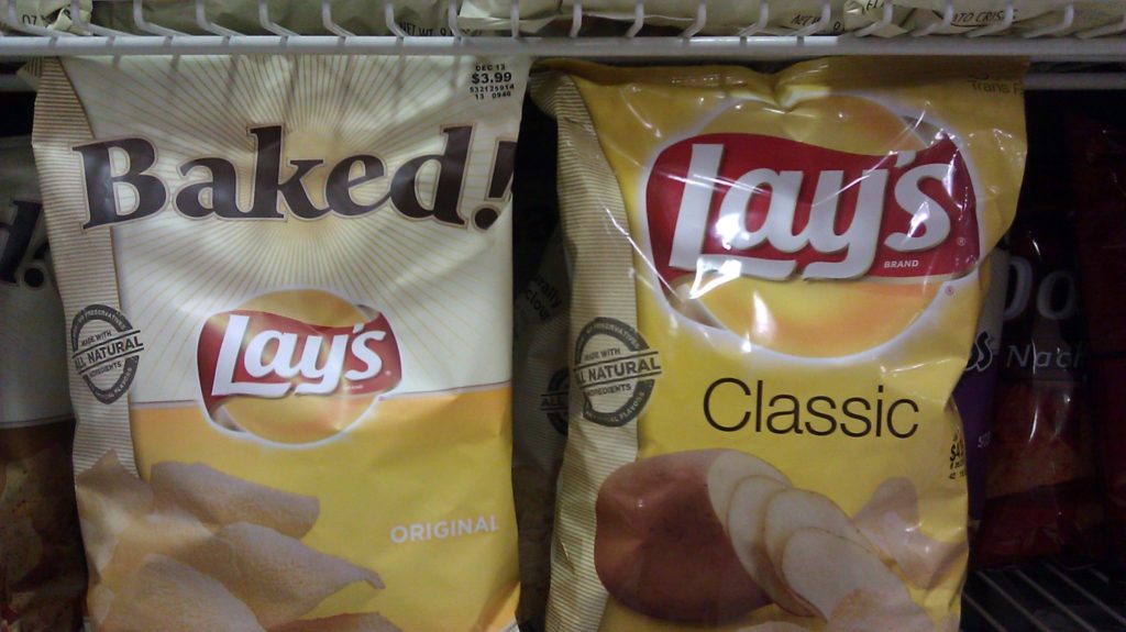 bags of fried and baked potato chips on a store shelf.
