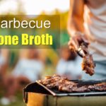 bone-in steaks and chicken on grill with man using tongs