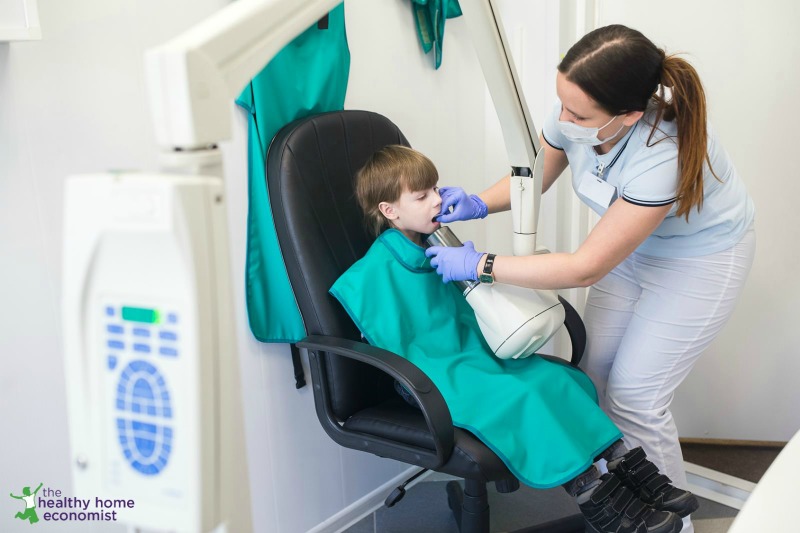 child in dental chair being exposed to x-rays without thyroid guard