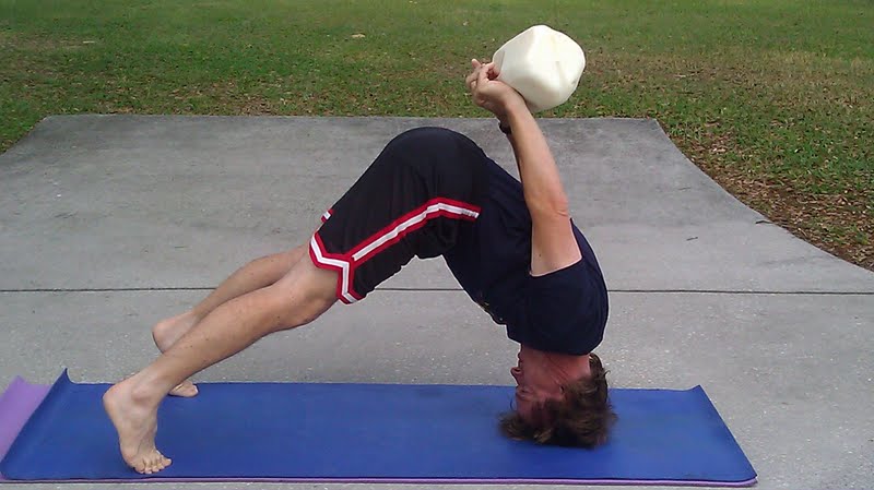 downdogonheadwithrawmilk man in yoga pose balancing a gallon of raw milk