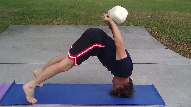 man in yoga pose balancing a gallon of raw milk