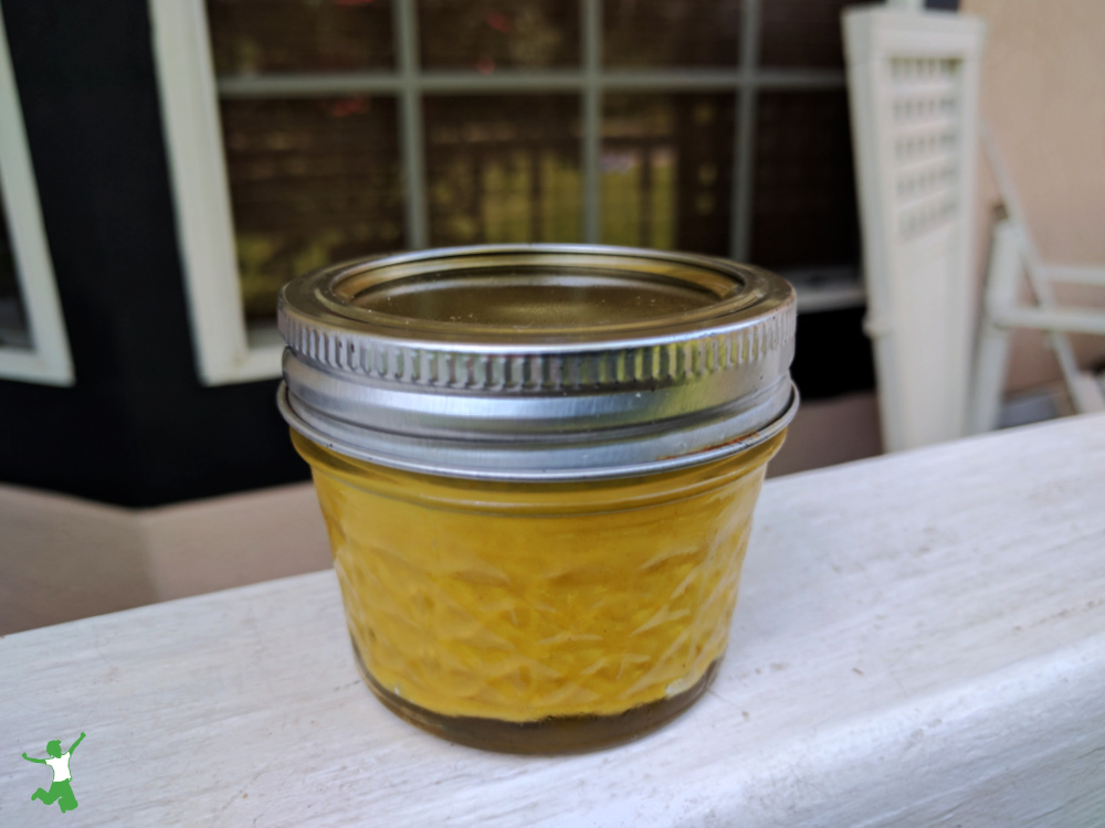jar of homemade fermented yellow mustard on porch rail