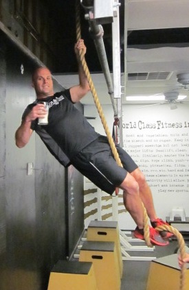 Man holding raw milk in a gym gripping a climbing rope