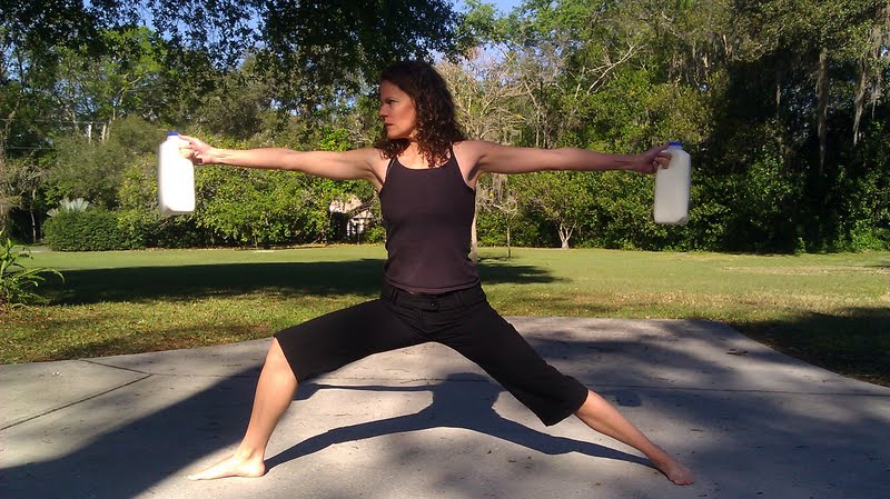 Woman holding two half gallons of raw milk in warrior 2 yoga pose