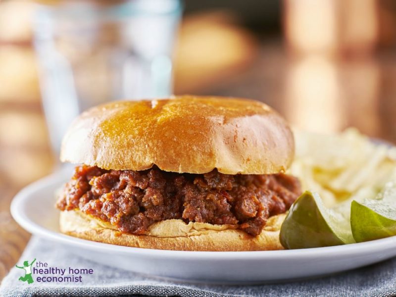 probiotic sloppy joe sandwich on white plate with pickle wedges