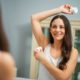 young woman applying roll-on in the bathroom