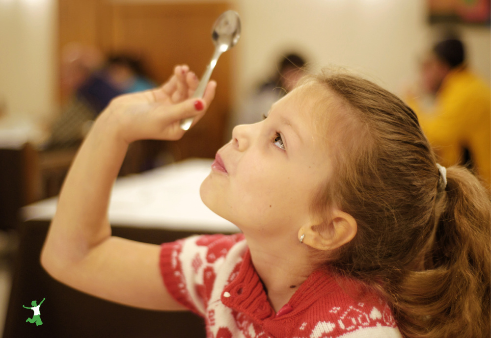 little girl taking cod liver oil off the spoon