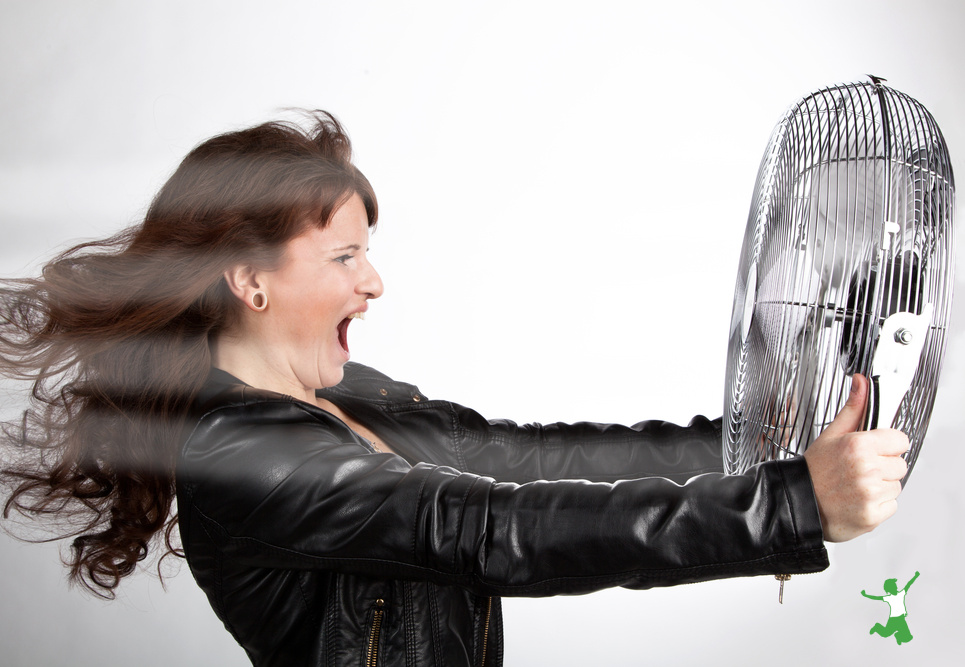 woman having a hot flash holding a fan