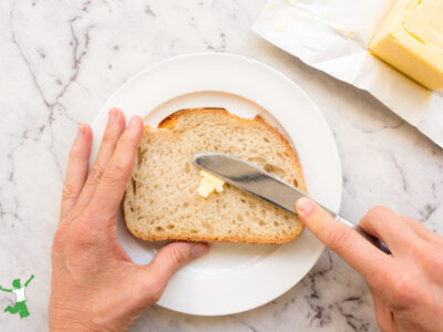 woman spreading butter on slice of sourdough bread