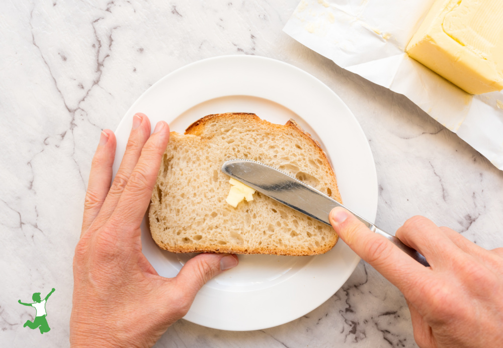 woman spreading butter on slice of sourdough bread
