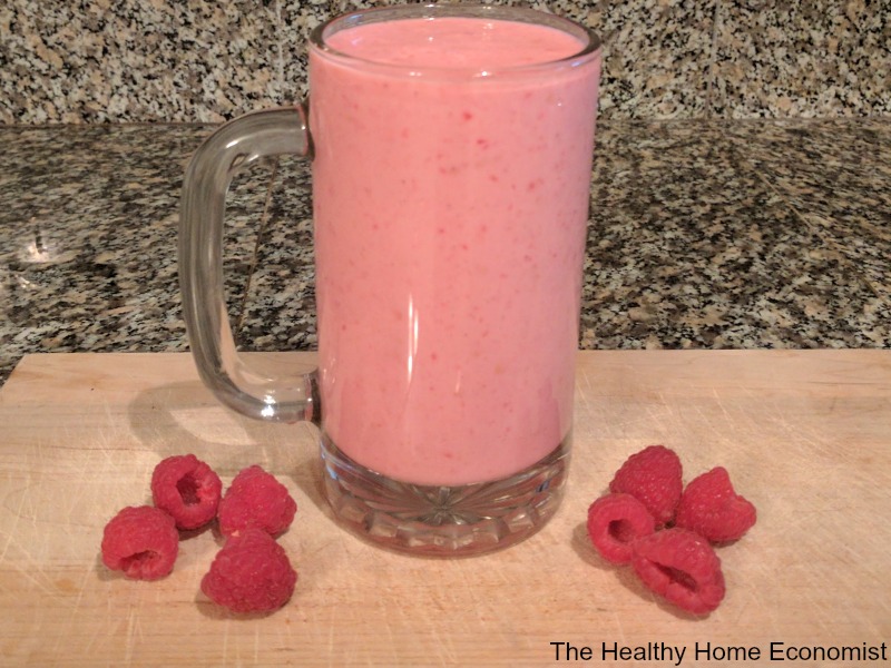 blended lassi yogurt drink on the counter with raspberries on a cutting board