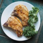 marinated pork chops on a white plate with vegetables