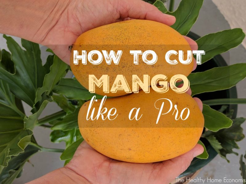 woman holding two mangos ready to be cut and pit removed