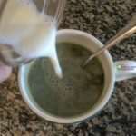 pouring frothed milk into matcha mug