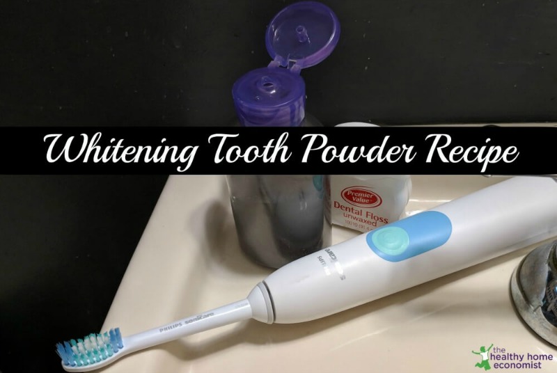 homemade tooth powder in a travel container on bathroom sink with a toothbrush and floss 