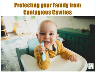 baby in high chair smiling while chewing on a spoon