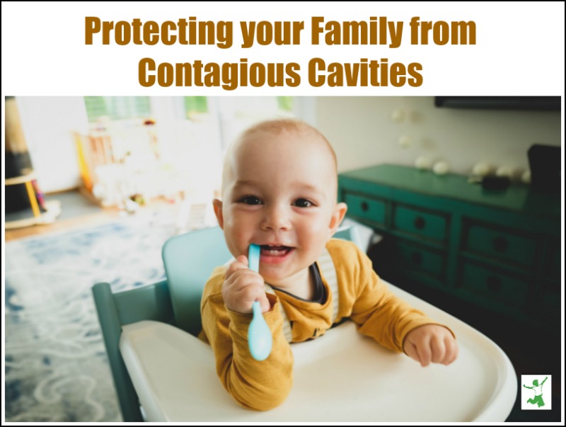 baby in high chair smiling while chewing on a spoon