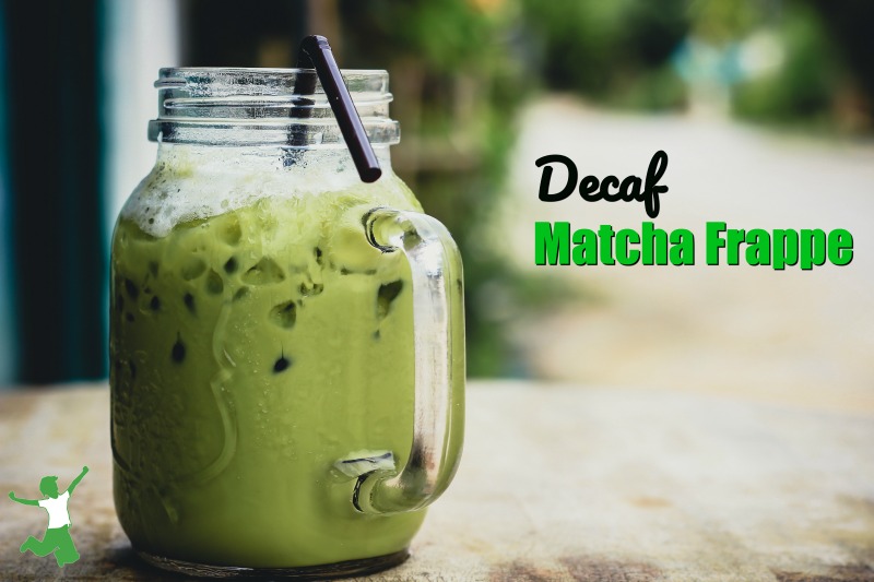 iced decaf matcha frappe in a glass mug with straw on a wooden table