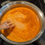 broth and milk blended into spices in a large pan