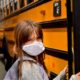 child wearing a mask boarding a school bus