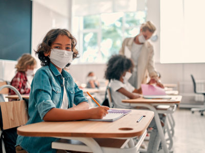 child wearing mask at school desk