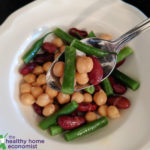 three bean salad in a white bowl with spoon