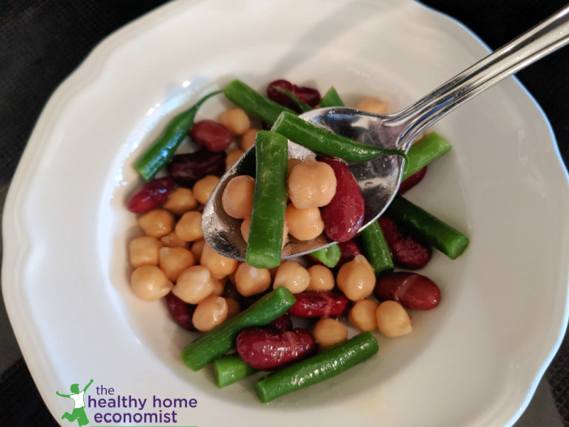 three bean salad in a white bowl with spoon