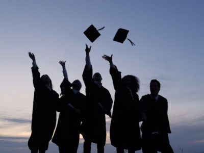 group of college graduates tossing their caps