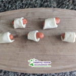 grassfed dogs rolled up in crescent roll dough on cutting board