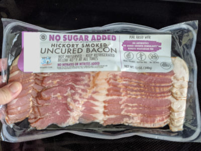 woman holding package of sugar-free bacon