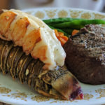 baked lobster tail on a white plate with vegetables