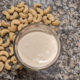 cashew cream in a glass measuring cup with cashews on counter