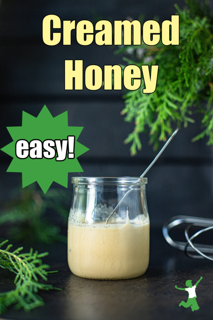 small glass jar of homemade creamed honey on black background