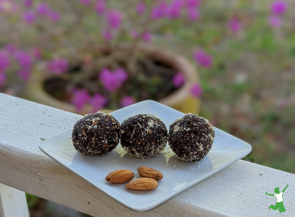 almond butter chocolate energy balls on white plate with flower background