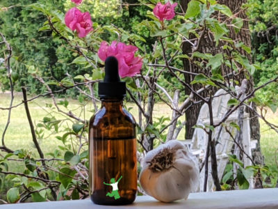 amber dropper bottle of garlic ear oil drops flower background